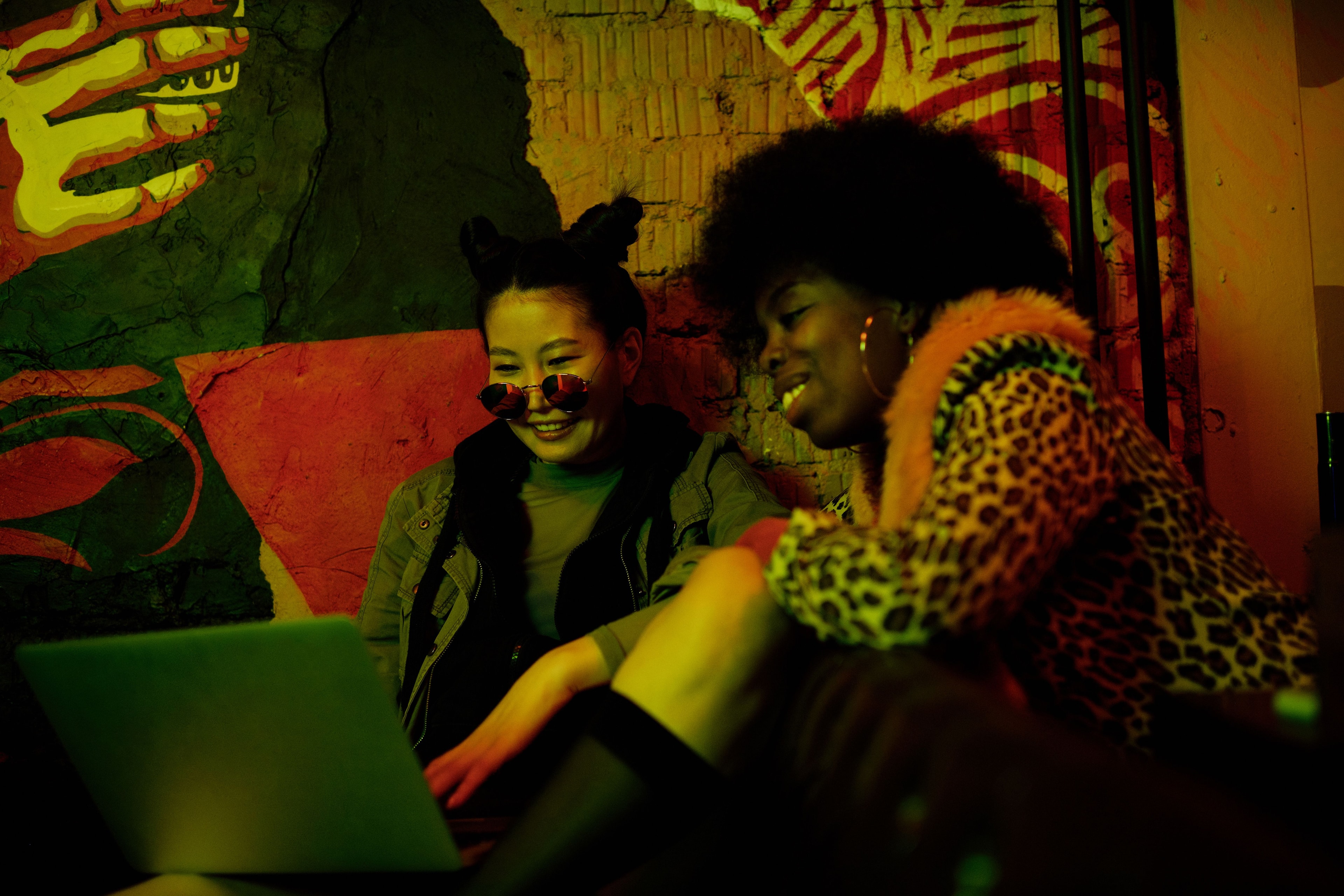 Two people working together over a laptop in a studio with painted walls