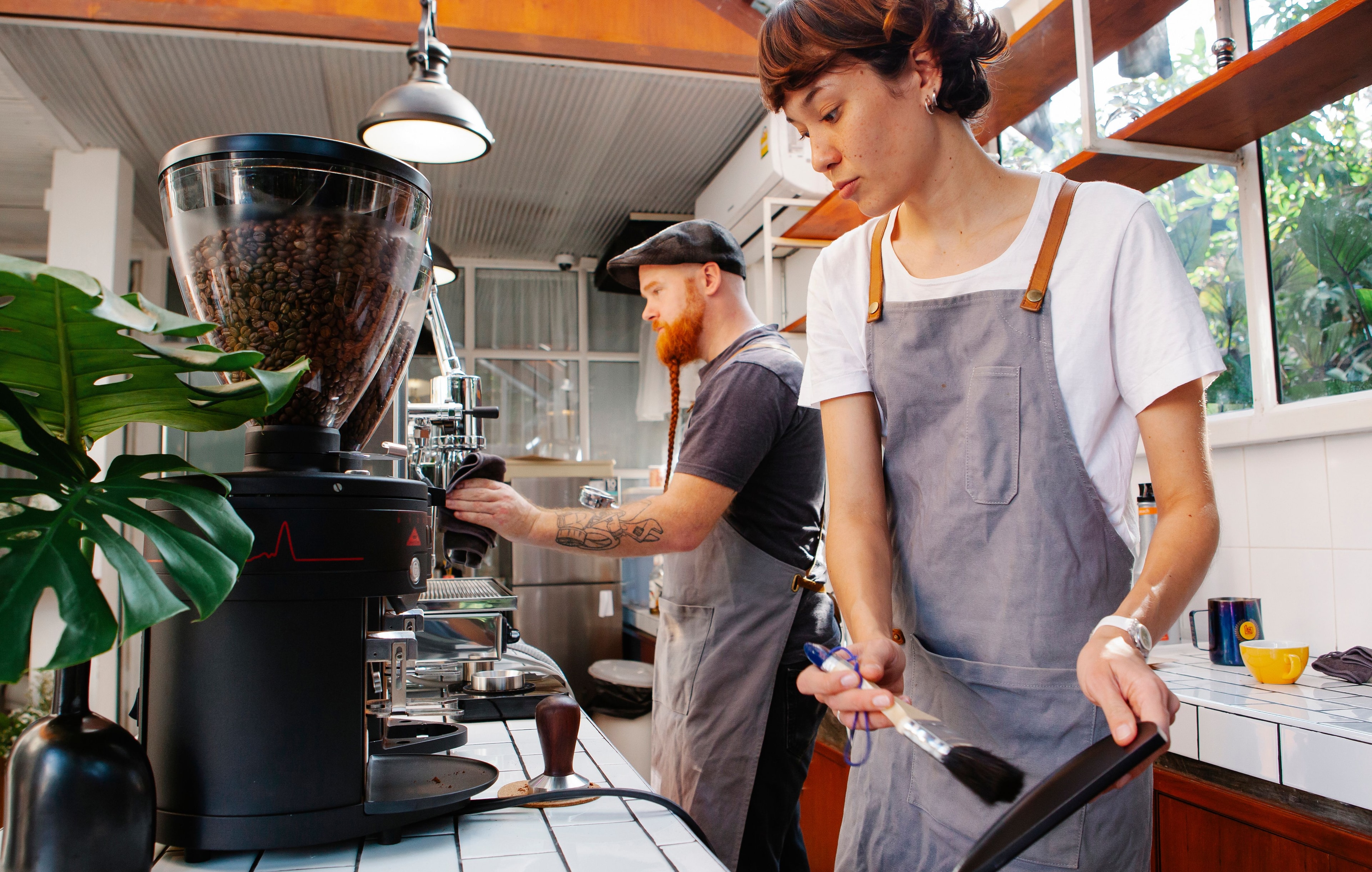 Two baristas working behind the counter of a coffee shop